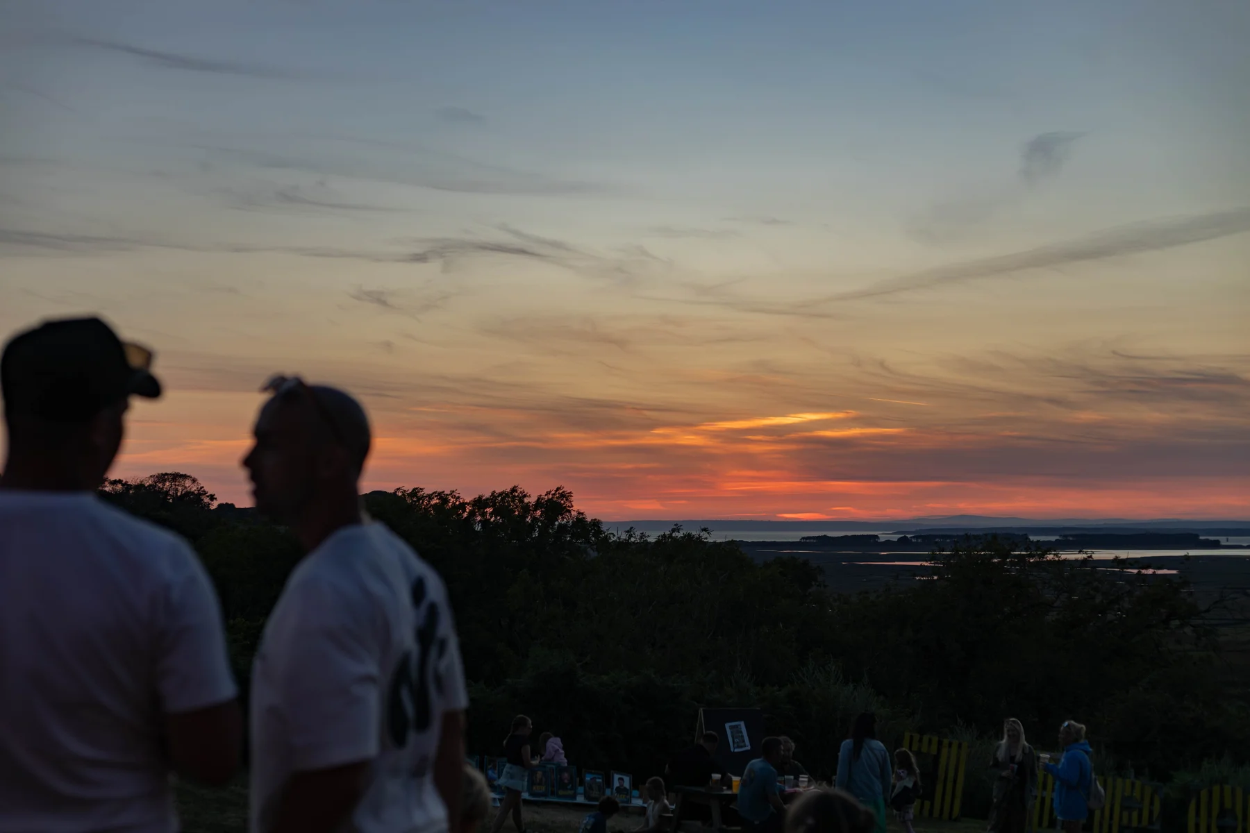 Festival visitors watching a golden Gower sunset